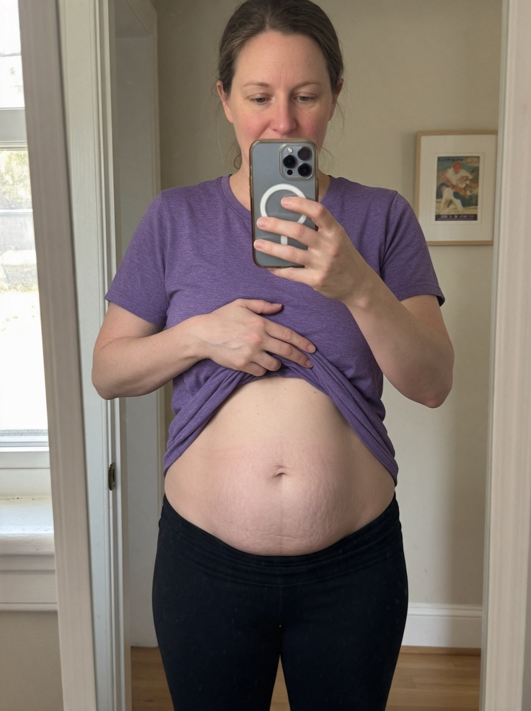 Woman photographing her postpartum stomach in a mirror